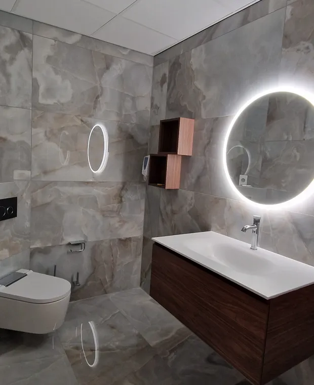 Salle de bains avec carrelage effet pierre, vasque et miroir rond lumineux